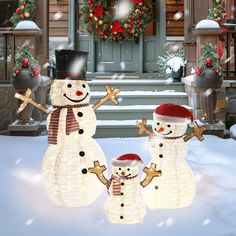 three lighted snowmen standing in front of a house