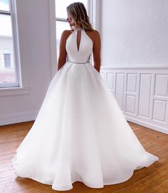 a woman in a white dress standing on a wooden floor with her back to the camera