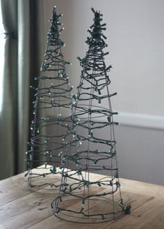 two metal christmas trees sitting on top of a wooden table