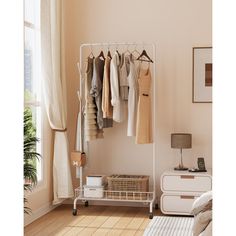 an organized closet with clothes hanging on the rails and baskets under it, along with a bed