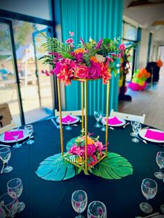 the centerpiece is decorated with pink flowers and greenery on a blue table cloth