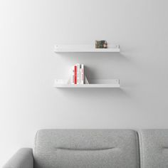 two white bookshelves on the wall above a gray couch in a living room