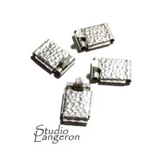 four pieces of silvertoned metal are arranged in the shape of small rectangles