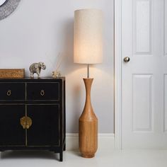 a wooden lamp next to a black dresser