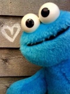 a close up of a stuffed animal near a wall with graffiti on it's face