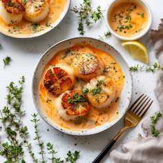 two bowls filled with soup and topped with scallops