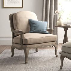 a living room with a chair, table and vase on the floor in front of a window