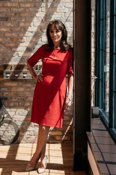 a woman in a red dress standing on a porch