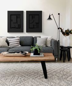 a living room with two black and white paintings on the wall next to a gray couch