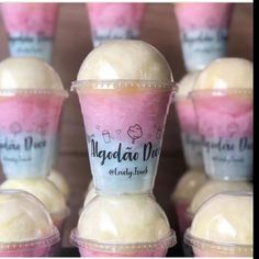 several ice creams in plastic cups with pink and white frosting on them, all lined up