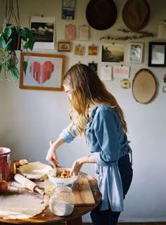 a woman standing in front of a counter cutting food on top of a wooden table