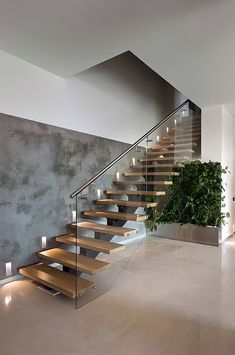 a modern staircase with wooden steps leading up to the second floor and potted plant