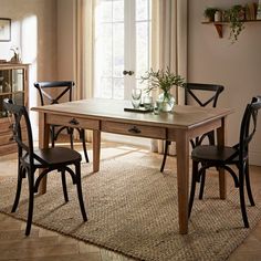 a dining room table with two chairs and a vase on the table next to it