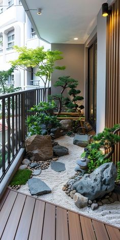 a small garden with rocks and plants on the outside deck area, next to a balcony