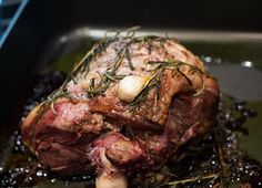 a piece of meat sitting on top of a pan covered in sauce and herbs next to garlic