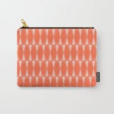 an orange and white geometric pattern carry - all pouch with gold zipper closure on the front