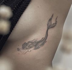 a woman's stomach with a tattoo of a fish on the side that is black and white