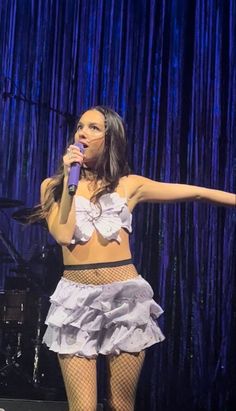 a woman in fishnet stockings on stage holding a microphone