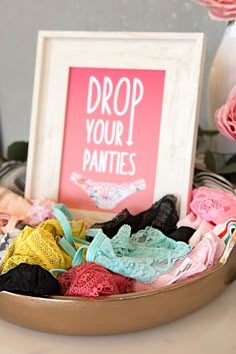 there is a sign that says drop your panties on the table next to some bras