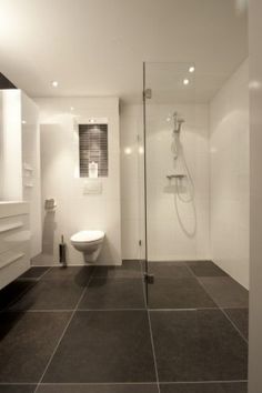 a modern bathroom with black and white tile flooring, glass shower stall and toilet