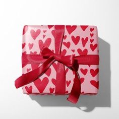 a present wrapped in pink and red paper with hearts on it