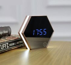 an alarm clock sitting on top of a wooden table next to a stack of books