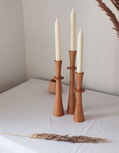 three candles are sitting on a white table cloth