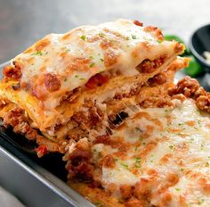 two pieces of lasagna stacked on top of each other in a metal pan