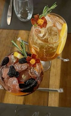 two glasses filled with drinks sitting on top of a wooden table