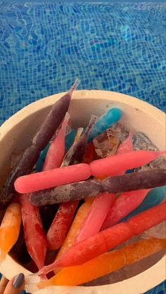 a bowl filled with candy sticks next to a swimming pool