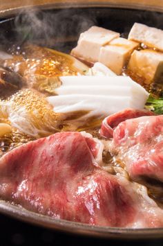 meat and vegetables cooking in a pan with steam rising from the top to the bottom