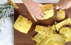 someone cutting up pineapple slices on a cutting board