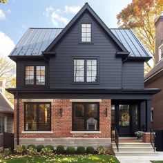 a black house with two story windows and a metal roof