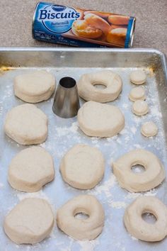 doughnuts are being made on a baking sheet with a can of biscuits in the background