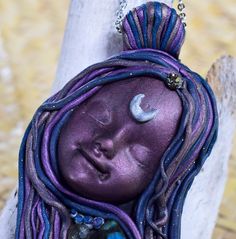 a close up of a purple and blue doll with a crescent on it's head