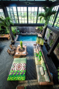 an indoor swimming pool with couches and tables next to each other in front of large windows