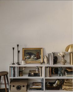 a bookshelf filled with lots of books next to a lamp and pictures on the wall