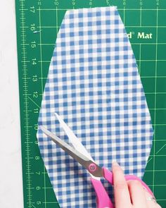 a person cutting up fabric with scissors on a cutting board next to a green mat