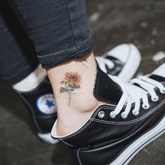 a sunflower tattoo on the ankle is shown in black and white shoes, with an upper