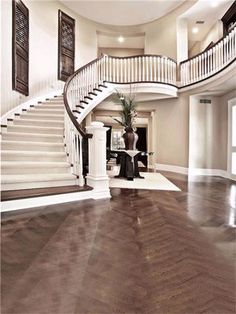 a large foyer with white stairs and wood floors