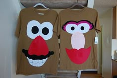 two t - shirts with faces are hanging on a rack