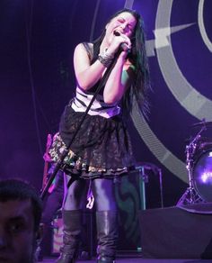 a woman standing on stage holding a microphone in her hand and singing into the microphone