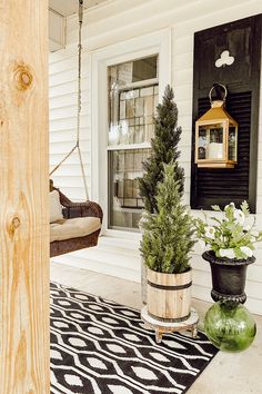 the porch is decorated with potted plants and hanging from chains on the front door