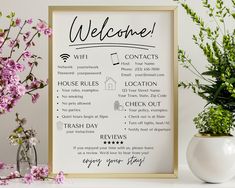 a welcome sign next to a potted plant and vase with pink flowers on it