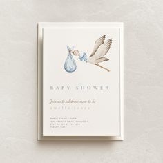 a baby shower card with a stork carrying a baby in a blue bag