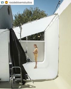 a woman is standing in front of a white backdrop with black cloths on it