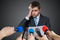 a man in a suit surrounded by microphones