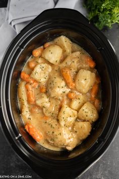 a crock pot filled with potatoes and carrots