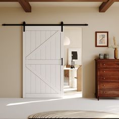 a bedroom with a bed, dresser and sliding barn door