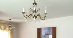 a chandelier hangs from the ceiling in a room with white walls and windows